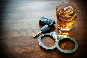 handcuffs next to a glass of whisky and car keys